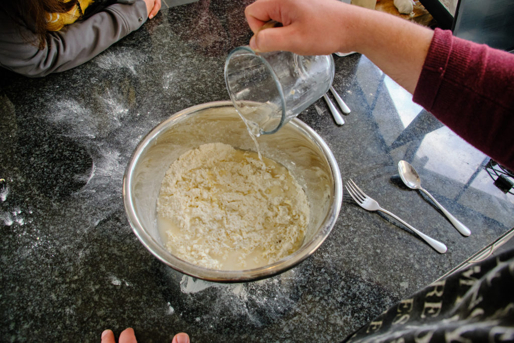 Add liquid to flour and butter mixture in preparation for making puff pastry from scratch.